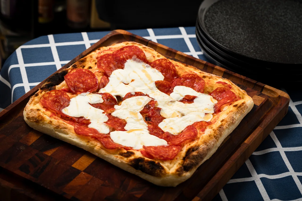 Pizza sobre uma tábua, pronta para compartilhar à mesa
